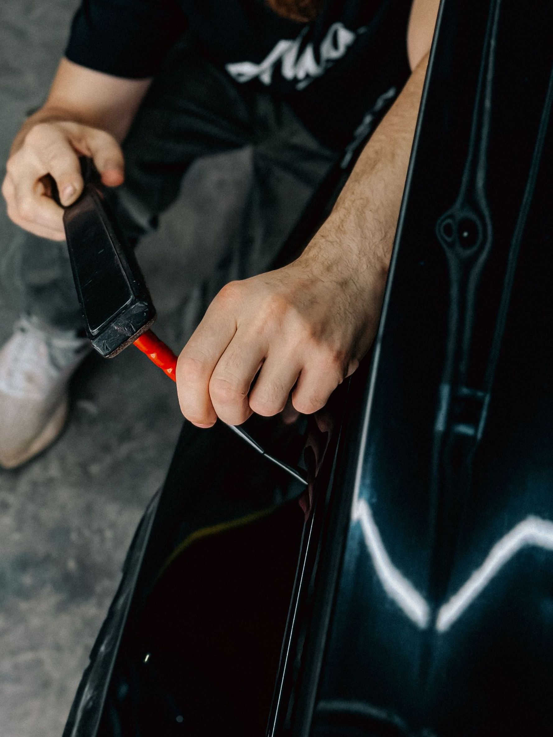 Mechanic uses tools to repair a car, showcasing hands-on automotive work indoors.