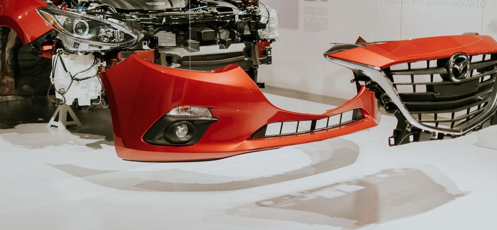 Explore a detailed view of a partially disassembled red Mazda 3 showcased at an auto exhibition.